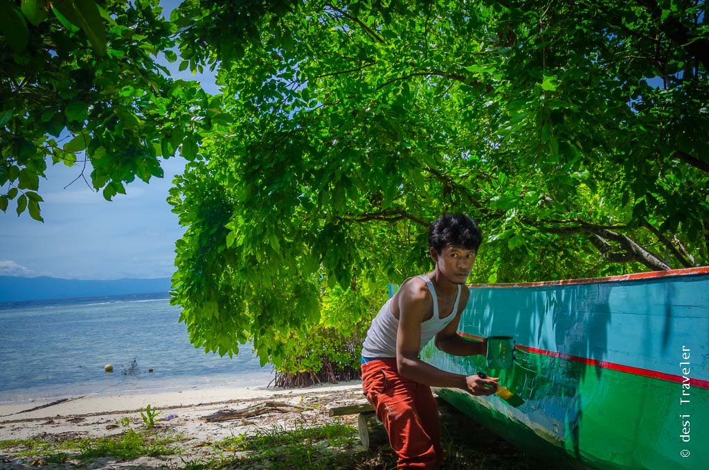 Man painting boat in Raja Ampat Arborek Village Indonesia